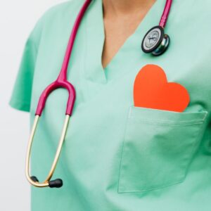 Estetoscópio e coração de papel no bolso do jaleco, representando cuidado cardiológico